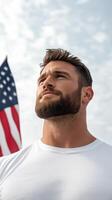 Young man stands proudly with an American flag in the background on a bright sunny day expressing patriotism and confidence photo