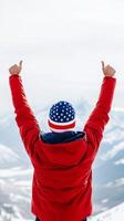 A person in a red jacket celebrates at a snowy mountain peak under a clear sky during winter, expressing joy and triumph photo