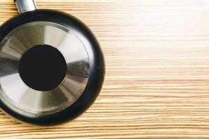 Frying pan on wooden table background. View from above photo