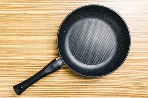 Frying pan on wooden table background. View from above photo