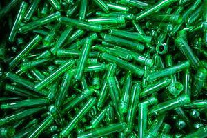 Collection of transparent green plastic tubes arranged randomly in a heap on a surface photo