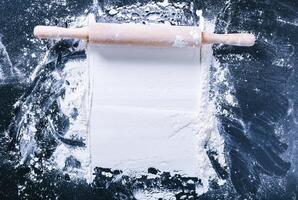 Baking desk with flour and rolling pin, top view photo