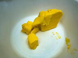 A close up of a chunk of yellow butter in a white bowl, showcasing its smooth texture and vibrant color, perfect for culinary and food related themes photo