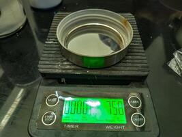 A close up of a digital scale displaying a weight of 75,8 grams with a metal container on top, used in a laboratory setting for precise measurements photo