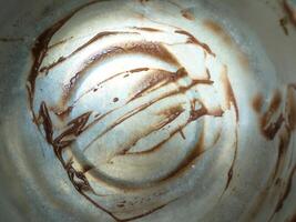 Chocolate smears on a metallic surface, creating an abstract pattern. The image captures the texture and shine of the chocolate against the metal, making it visually intriguing photo