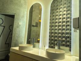 Modern bathroom with two round sinks, large mirrors, and stylish wall tiles. The design features a clean, minimalist aesthetic with a focus on functionality and elegance photo