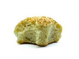 A close up of a partially eaten bread roll topped with shredded cheese. The texture of the bread is soft and fluffy, with a golden-brown crust photo