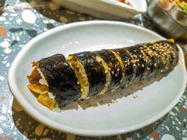 A close up of a delicious gimbap roll on a white plate, showcasing its vibrant ingredients and sesame seed topping, perfect for food enthusiasts and culinary photography photo