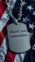 Thank you veterans displayed on a dog tag resting on an American flag photo