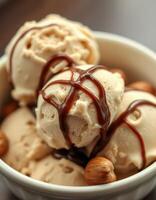 Creamy chocolate drizzled ice cream topped with hazelnuts in a bowl on a wooden table photo