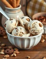 Creamy vanilla ice cream with chocolate chips and nuts served in a white bowl on a wooden table photo
