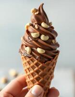 Rich chocolate soft serve ice cream topped with crunchy nuts served in a waffle cone during a sunny afternoon photo