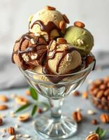 Ice cream sundae with mixed flavors topped with nuts and chocolate syrup in a glass dish photo