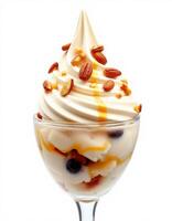 Delicious soft serve dessert topped with nuts and caramel sauce in a clear glass dish photo