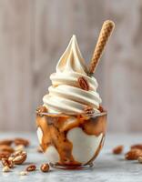 Delicious soft serve ice cream topped with caramel sauce and nuts served in a clear cup photo