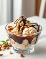 Delicious ice cream sundae topped with chocolate sauce and peanuts served in a clear glass bowl photo