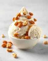 Delicious ice cream dessert topped with crunchy nuts served in a white bowl on a marble surface photo
