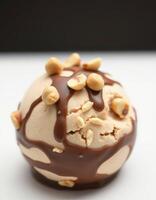 Delicious ice cream scoop topped with chocolate sauce and crushed nuts on a clean surface photo