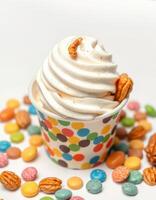 Creamy soft serve dessert topped with nuts and colorful candies in a festive cup on a bright background photo