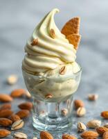 Creamy almond soft serve dessert served in a small glass with crunchy toppings and whole almonds scattered around photo