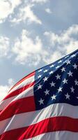 American flag waving proudly against a backdrop of blue sky and fluffy clouds during daytime photo
