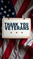 Sign honoring veterans displayed against a backdrop of an American flag, emphasizing gratitude and respect during a patriotic event photo