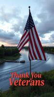 Flag waving above serene river landscape at sunset while honoring veterans with gratitude message photo
