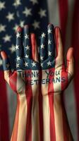Hands painted with American flag patterns express gratitude for veterans against a backdrop of a flag photo