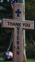 Wooden cross with message honoring veterans displayed outdoors in a serene setting photo