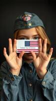 Young person holds a thank you veteran card displaying the American flag in a studio setting, showing appreciation for military service photo
