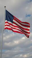 American flag waving against a cloudy sky, representing patriotism and freedom in a serene outdoor setting photo