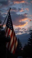 Soldier holding American flag during sunset with dramatic cloud formations in the background photo