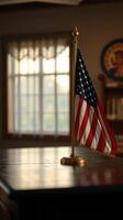 Small American flag stands on a polished wooden table in a sunlit room with a vintage decor photo
