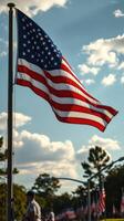United States flag waving proudly under a bright sky with scattered clouds at an outdoor event photo