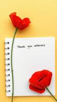 Expressing gratitude to veterans with a handwritten note and red poppy flowers on a bright yellow background photo