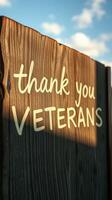 Sign honoring veterans displayed on a wooden fence under a clear blue sky during daylight photo