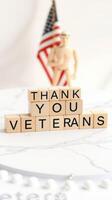 Wooden blocks spell message of gratitude to veterans with flag symbol in background photo