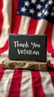 Thank you message for veterans placed on a textured stone against a backdrop of an American flag photo