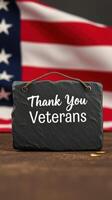 Slate sign with message honoring veterans against background of American flag photo