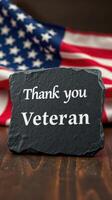 Thank you veteran sign displayed against an American flag background during a commemorative event photo