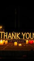Brightly lit message honoring veterans at a nighttime memorial event with candles photo