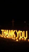 Brightly lit thank you sign surrounded by candles at night, conveying gratitude and appreciation in a serene setting photo