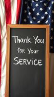 Sign expressing gratitude for military service in front of an American flag backdrop photo