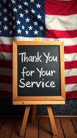 Sign expressing gratitude for service displayed against a backdrop of an American flag photo