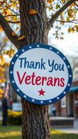 Thank you veterans sign attached to a tree in a local park during autumn with yellow leaves falling photo