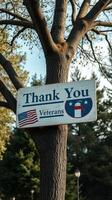 Sign honoring veterans displayed on a tree in a public park during daylight hours photo