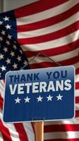 Sign expressing gratitude to veterans against a backdrop of an American flag photo