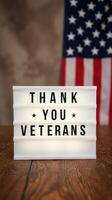 Sign expressing gratitude to veterans with American flag background in a warm indoor setting photo