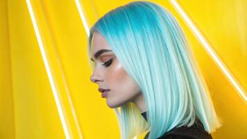 A closeup portrait of a person with sleek straight hair exhibiting bright icy blue highlights. Set against a vibrant yellow neon background the highlights shimmer in contrast. photo