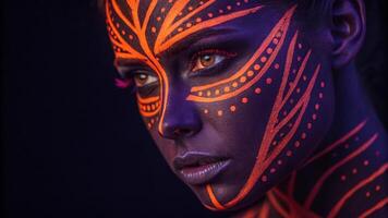A dramatic closeup of a young womans face painted in striking neon orange and bold violet. The face paint features sharp lines and intricate dots that highlight the contours of her. photo